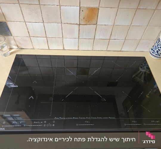 כיריים אינדוקציה שחורות על משטח שיש במטבח